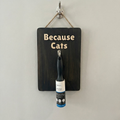 Wooden sign with 'Because Cats' text and a bottle of catnip roller on a white background